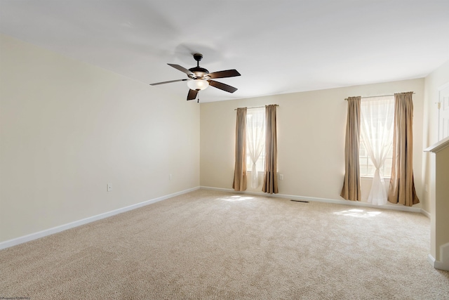empty room featuring carpet floors, visible vents, a ceiling fan, and baseboards