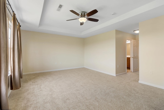 unfurnished room featuring a raised ceiling, visible vents, baseboards, light carpet, and a ceiling fan
