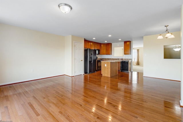 unfurnished living room featuring light wood-style floors, recessed lighting, a notable chandelier, and baseboards