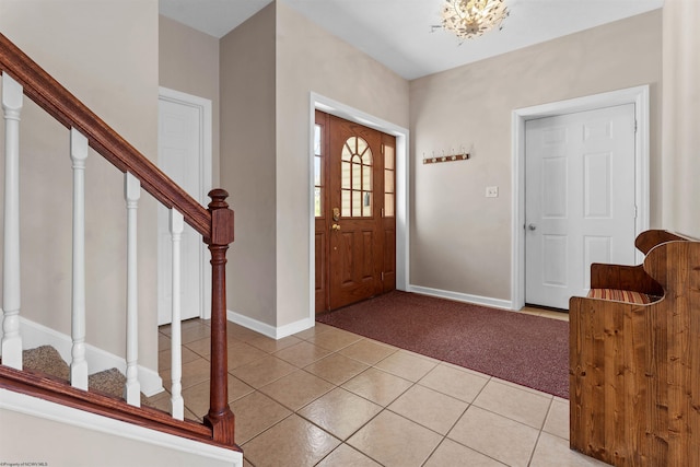entryway with a chandelier, light tile patterned floors, stairs, light carpet, and baseboards