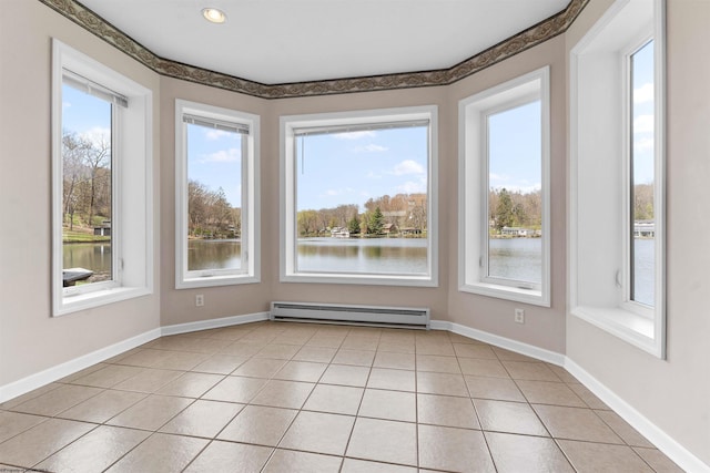 unfurnished room featuring a baseboard heating unit, light tile patterned flooring, a water view, and a wealth of natural light