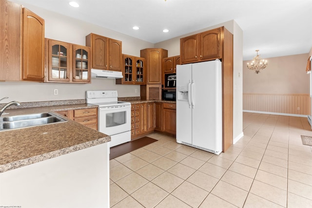 kitchen featuring a sink, under cabinet range hood, light tile patterned flooring, a notable chandelier, and white appliances