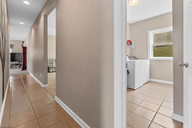 corridor with baseboards, recessed lighting, light tile patterned floors, and washing machine and dryer