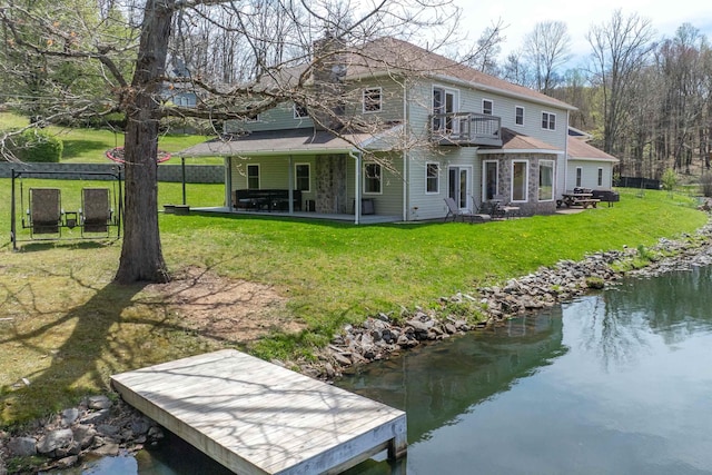 rear view of house featuring a patio, a balcony, a water view, and a lawn