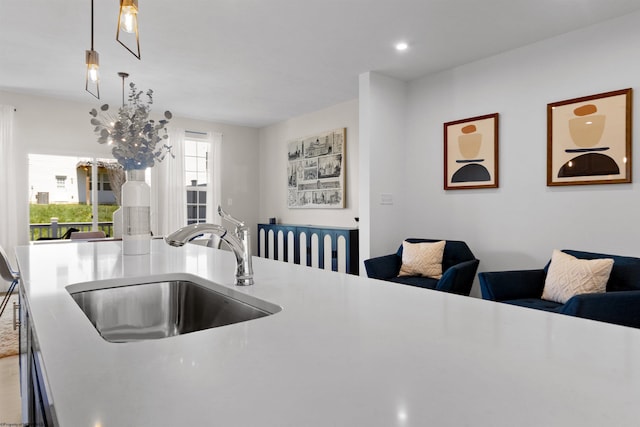 kitchen featuring decorative light fixtures, open floor plan, light countertops, and a sink