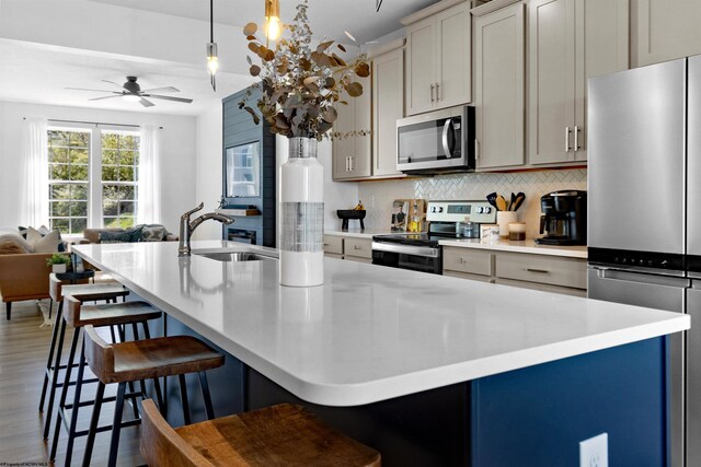 kitchen with a sink, appliances with stainless steel finishes, ceiling fan, open floor plan, and backsplash