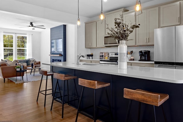 kitchen featuring ceiling fan, wood finished floors, a breakfast bar, appliances with stainless steel finishes, and open floor plan