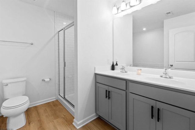 full bath featuring toilet, a stall shower, a sink, and wood finished floors