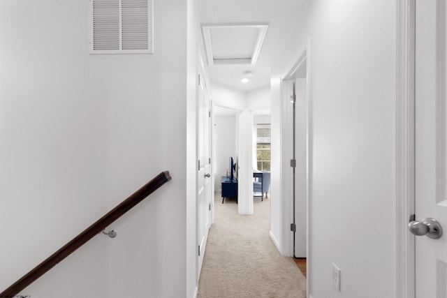 hall featuring attic access, an upstairs landing, visible vents, and light colored carpet