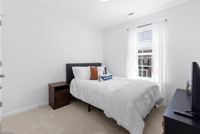 bedroom featuring visible vents, baseboards, and light carpet