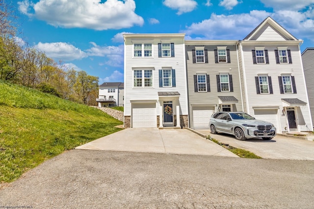 view of property with driveway, an attached garage, and stone siding