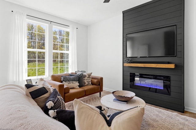 living area with baseboards, wood finished floors, and a glass covered fireplace