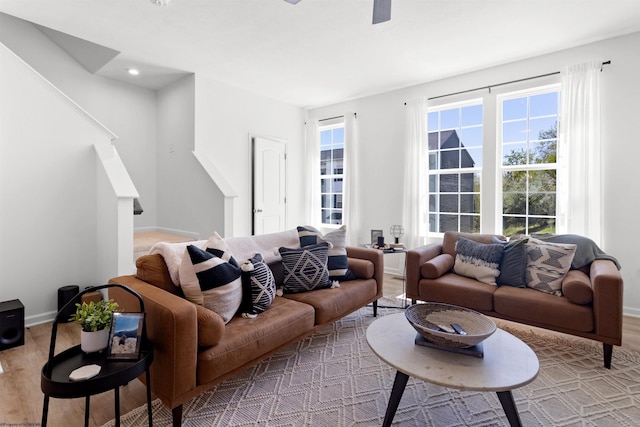 living area with baseboards, wood finished floors, ceiling fan, and stairs