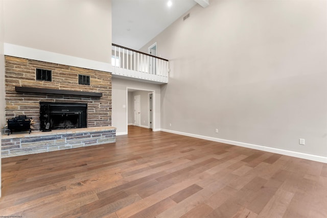 2254 Lakeside Ests, Morgantown, WV 26508 - unfurnished living room featuring a stone fireplace, visible vents, wood finished floors, high vaulted ceiling, and baseboards