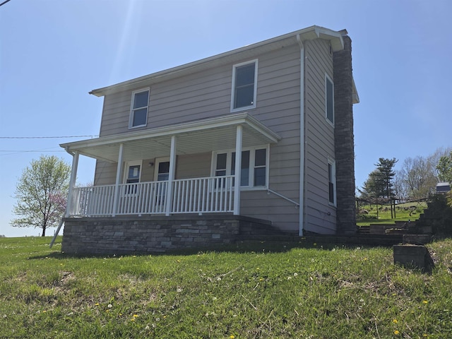 view of front of property with a porch, a chimney, and a front lawn
