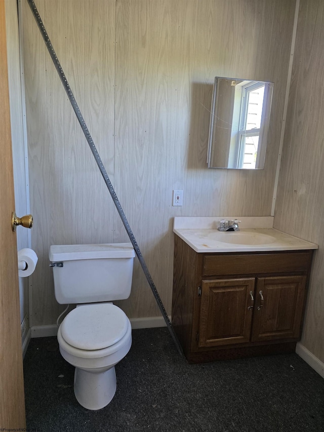 half bathroom with toilet, baseboards, and vanity