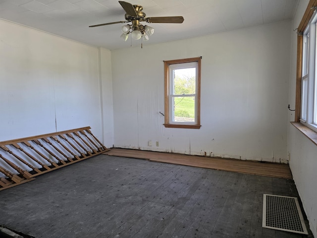 empty room featuring a ceiling fan, visible vents, and hardwood / wood-style flooring
