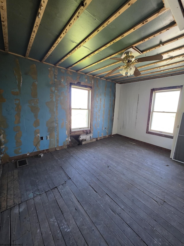 unfurnished room with ceiling fan, visible vents, a healthy amount of sunlight, and hardwood / wood-style floors
