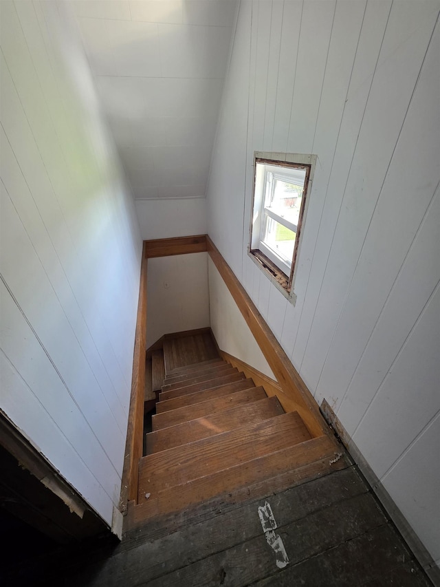 stairway with wood walls and lofted ceiling