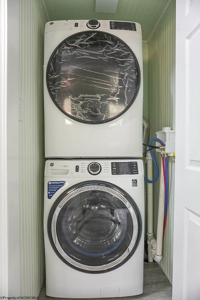 laundry area featuring laundry area, stacked washer / drying machine, and wood finished floors