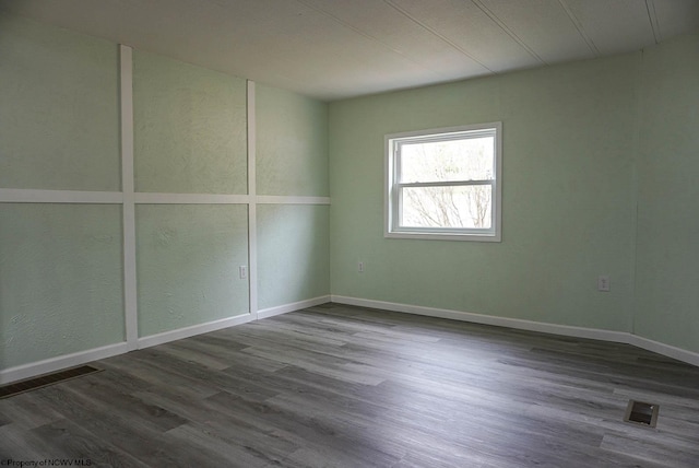 unfurnished room featuring baseboards, visible vents, and dark wood-style floors