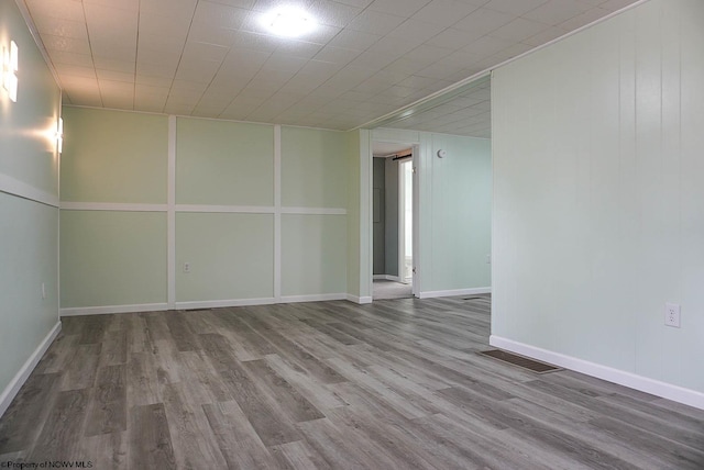 spare room featuring baseboards, visible vents, and wood finished floors