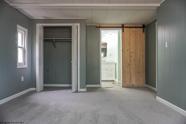 unfurnished bedroom with a closet, carpet flooring, connected bathroom, and a barn door