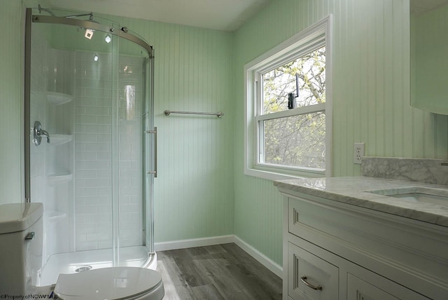 full bathroom with a stall shower, wood finished floors, vanity, baseboards, and toilet