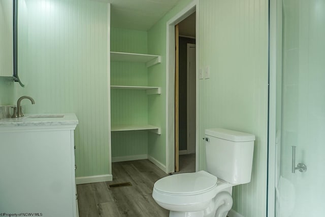 bathroom with vanity, visible vents, wood finished floors, toilet, and baseboards
