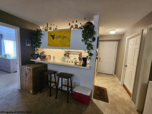 bar featuring tile patterned floors, white electric range oven, and a textured ceiling