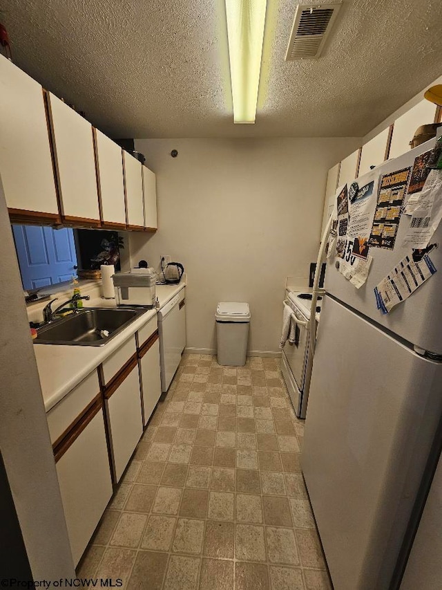 kitchen featuring a sink, white cabinets, white appliances, and visible vents