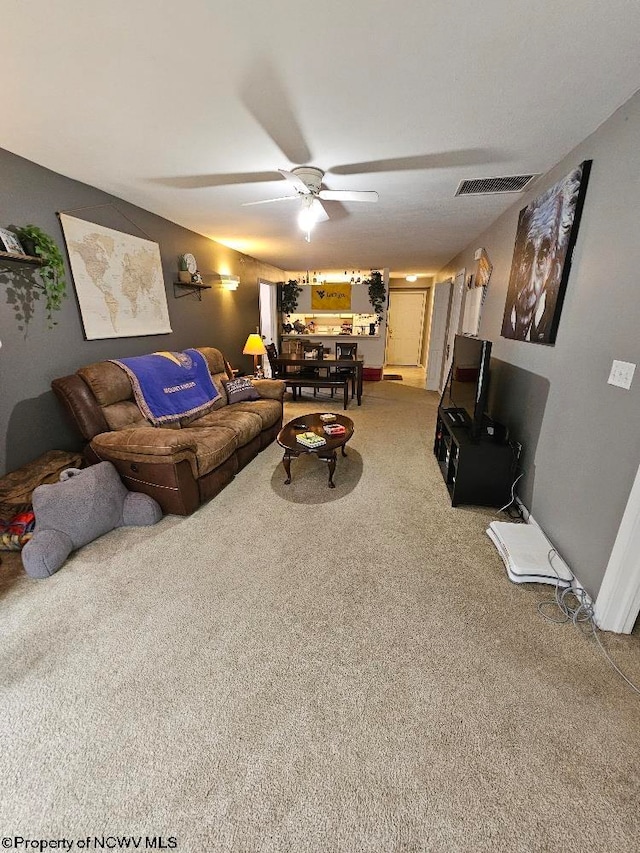 living room featuring visible vents, carpet floors, and ceiling fan