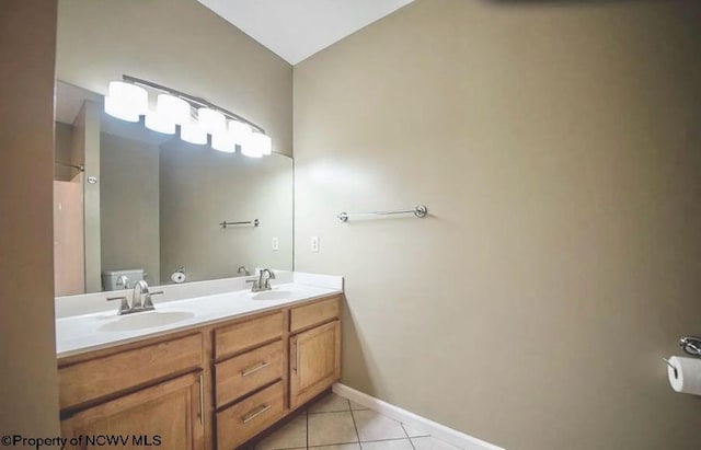 bathroom with tile patterned flooring, double vanity, lofted ceiling, baseboards, and a sink