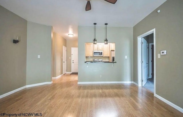 unfurnished living room featuring a ceiling fan, baseboards, and light wood-style flooring