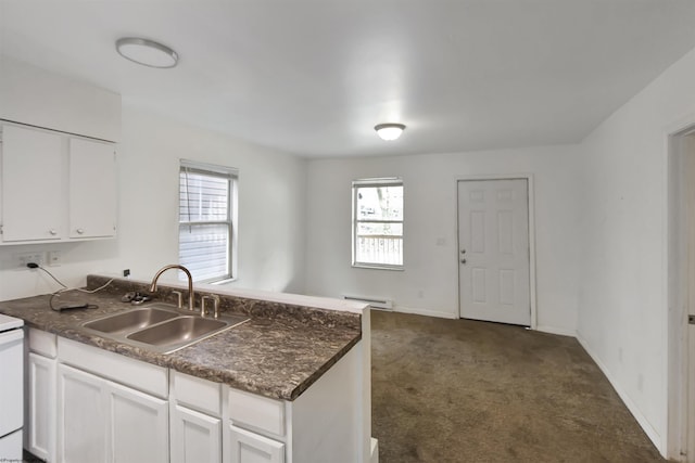kitchen with a peninsula, dark countertops, dark colored carpet, a baseboard radiator, and a sink