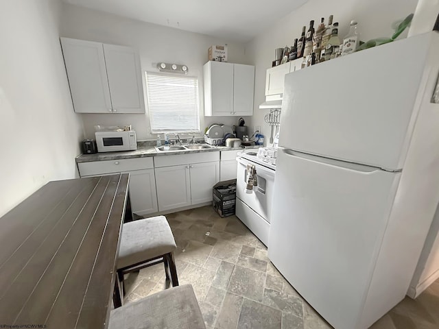 kitchen featuring white cabinets, a sink, white appliances, stone finish floor, and under cabinet range hood