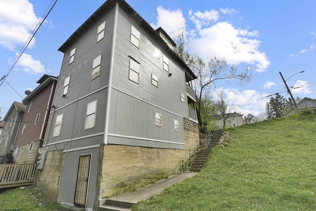 view of home's exterior with stairs and a yard