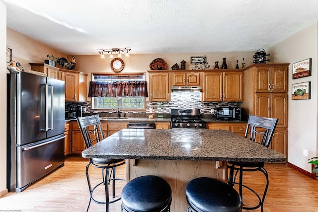 1252 Monumental Rd, Fairmont, WV 26554 - kitchen featuring backsplash, a kitchen bar, a sink, stainless steel appliances, and light wood-style flooring