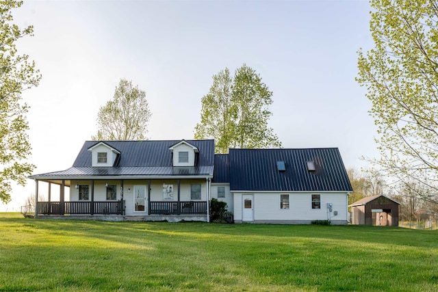rear view of house featuring covered porch, a lawn, metal roof, and an outdoor structure