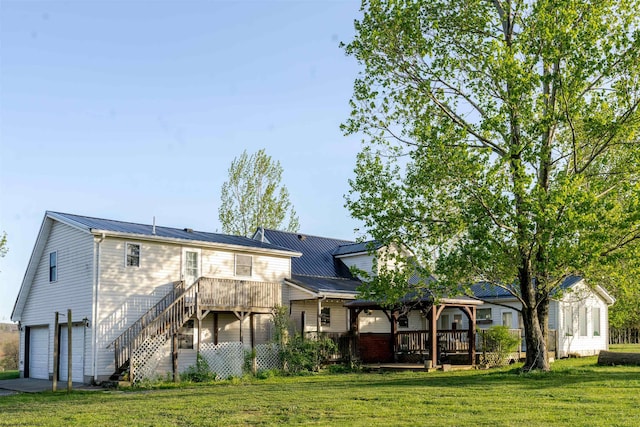 rear view of property with a wooden deck, an attached garage, and a yard
