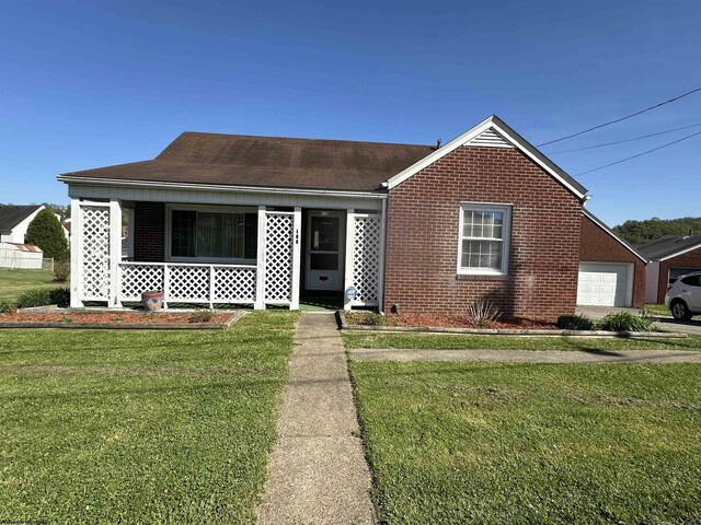 view of front of property featuring brick siding, a shingled roof, a front yard, and a porch
