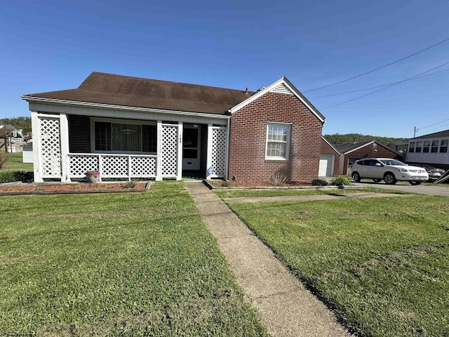 bungalow featuring brick siding, a garage, covered porch, and a front yard