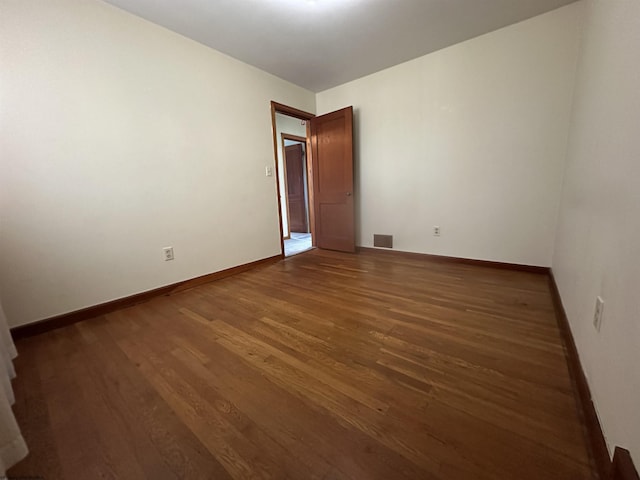 spare room featuring baseboards, visible vents, and wood finished floors