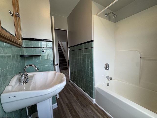 bathroom featuring wainscoting, shower / bathtub combination, wood finished floors, tile walls, and a sink