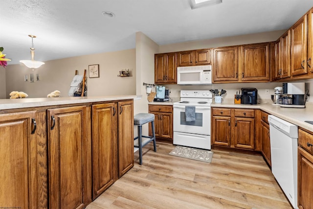 kitchen with white appliances, light countertops, brown cabinetry, and light wood-type flooring