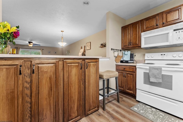 kitchen featuring brown cabinetry, light wood finished floors, and white appliances
