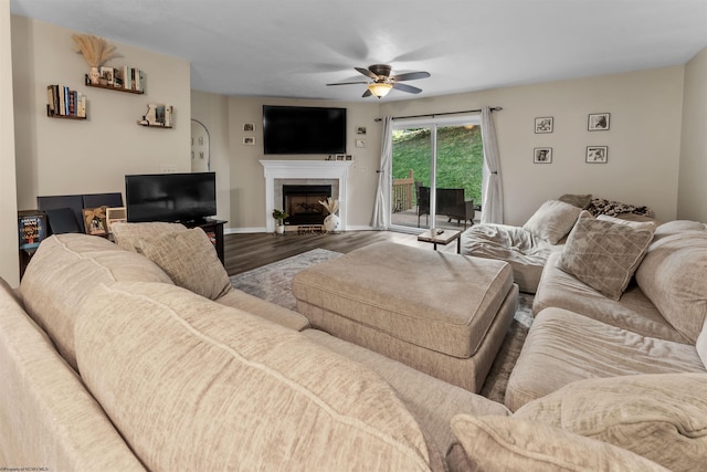 living area with baseboards, a fireplace, a ceiling fan, and wood finished floors