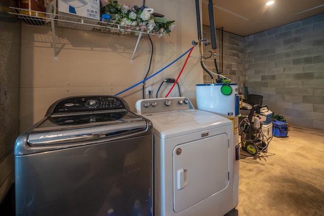 laundry room featuring concrete block wall, laundry area, and independent washer and dryer