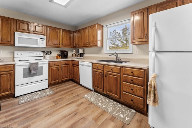 kitchen featuring brown cabinetry, white appliances, light wood-style floors, light countertops, and a sink