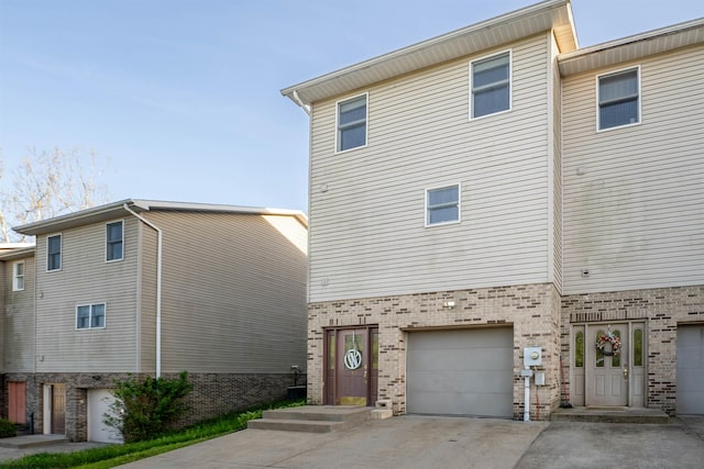 view of front of house with a garage, concrete driveway, and brick siding